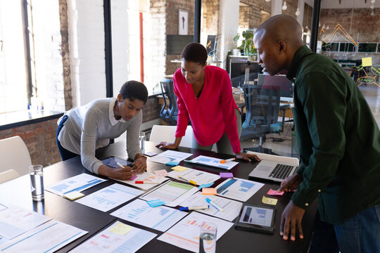 African american colleagues with documents and graphs on table discussing work in office