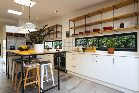 Interior of modern kitchen with dining table, stools, cooking pans and pasta ingredients on counter