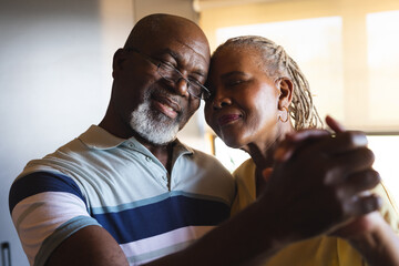 Happy senior african american couple embracing and dancing at home