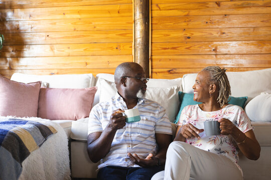 Happy Senior African American Couple Sitting On Floor And Drinking Coffee At Home