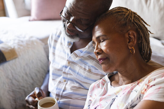 Thoughtful senior african american couple sitting on floor and drinking coffee at home