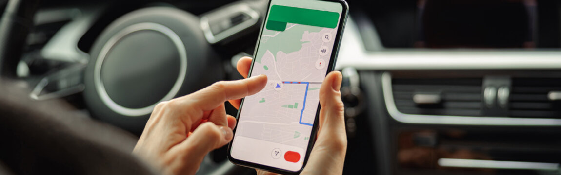 Closeup of female traveler using cell phone with gps navigation app on screen while sitting in car