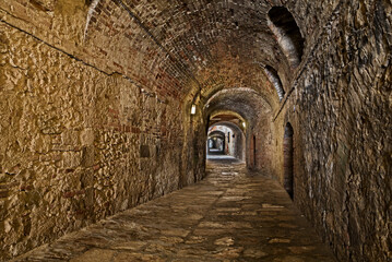 Fototapeta premium Colle di Val d'Elsa, Siena, Tuscany, Italy: the ancient covered alley Via delle Volte, a medieval dark passage in the old town