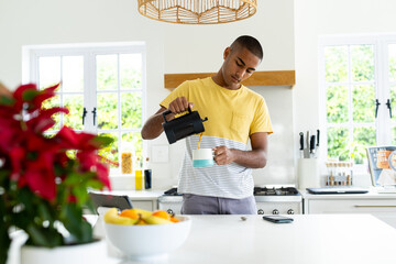 Biracial man pouring cup of coffee in sunny kitchen