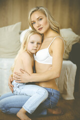 Happy mom and little daughter cuddle while dressing. Motherhood and family concept