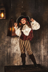 Full length of pirate posing on chest in underground room or hold of pirates ship, playful looking...