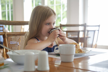 Cute 5 years old girl eating chocolate muffin at the restaurant	