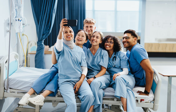Group of diverse medical students taking a selfie together on a hospital bed