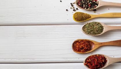 Spices in spoons and scattered on a white background with space for text