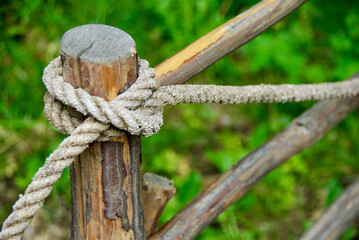 Rope tied with a clove hitch around a wooden fence pole. 