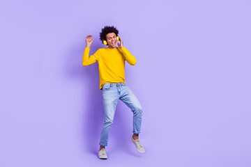 Fototapeta na wymiar Full length photo of crazy funny youngster guy listen his new sony wireless headphones rock roll music isolated on purple color background