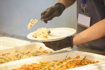 Buffet style service - Canteen worker at serving line putting food on the plate