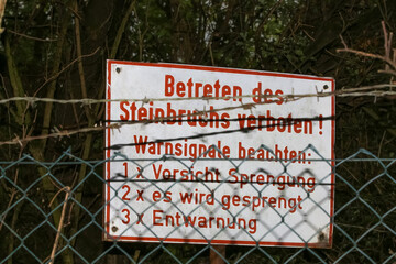 Schild mit Aufschrift Betreten des Steinbruchs verboten, Warnsignale beachten, Vorsicht Sprengung
