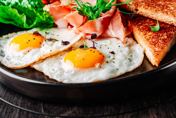 fried eggs with ham, salad and toast