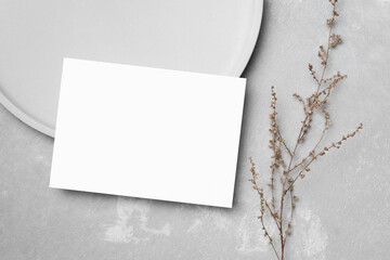 Fototapeta na wymiar Blank greeting card mockup with dry botanical decor on grey background, white card with copy space