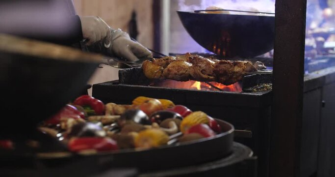 Close up cooking street food. Juicy meat kebab and vegetables  fried on coals on the grill. Picnic or evening barbecue. Winter fair, outdoor trade.