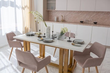 stylish kitchen and a set dining table in a light luxury interior design of a modern apartment in a minimalist style with marble trim and huge windows. daylight inside.
