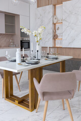 stylish kitchen and a set dining table in a light luxury interior design of a modern apartment in a minimalist style with marble trim and huge windows. daylight inside.