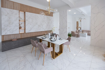 stylish kitchen and a set dining table in a light luxury interior design of a modern apartment in a minimalist style with marble trim and huge windows. daylight inside.