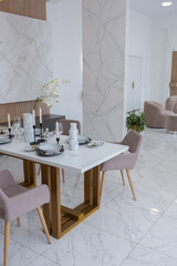 stylish kitchen and a set dining table in a light luxury interior design of a modern apartment in a minimalist style with marble trim and huge windows. daylight inside.