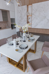 stylish kitchen and a set dining table in a light luxury interior design of a modern apartment in a minimalist style with marble trim and huge windows. daylight inside.