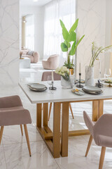 stylish kitchen and a set dining table in a light luxury interior design of a modern apartment in a minimalist style with marble trim and huge windows. daylight inside.