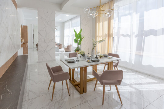 stylish kitchen and a set dining table in a light luxury interior design of a modern apartment in a minimalist style with marble trim and huge windows. daylight inside.
