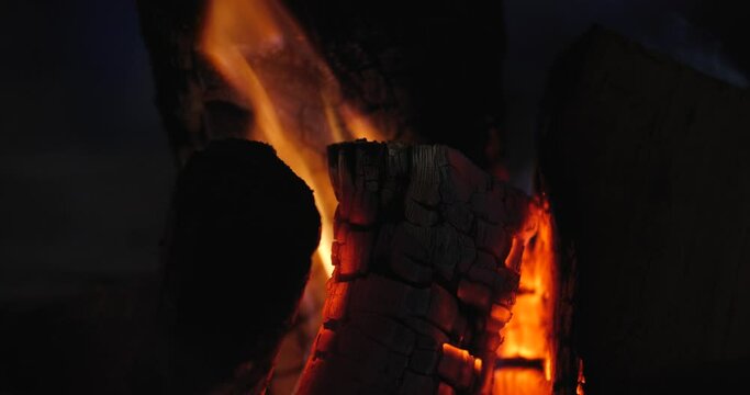 Extreme close-up of a burning hearth. Wooden logs smolder brightly in the fire. Beautiful background with copy space. Bright flames of fire over black background, slow motion 50 fps 4k