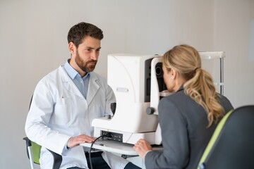 Optometrist checks the patient's intraocular pressure in optician's shop or ophthalmology clinic - obrazy, fototapety, plakaty