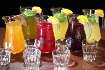 Cold lemonades. Berry Lemonade. Quenching thirst and refreshing drinks. Lemonade in the jug and lemons with mint on the table indoor.