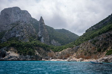 kamieniste i obrośnięte zieloną roślinnością zbocza wyspy Sardynia, widok z motor&oacute;wki, plaża