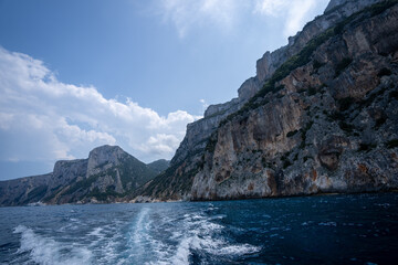 kamieniste i obrośnięte zieloną roślinnością zbocza wyspy Sardynia, widok z motorówki, fale © Arkadiusz