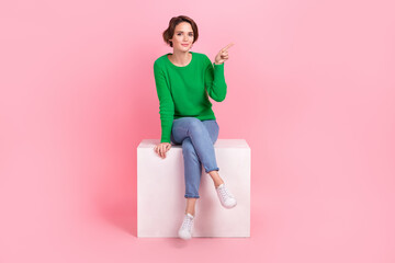 Full length photo of adorable pretty girl dressed green sweater pointing finger empty space isolated pink color background