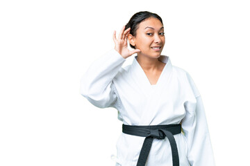 Young Uruguayan woman doing karate over isolated chroma key background listening to something by putting hand on the ear