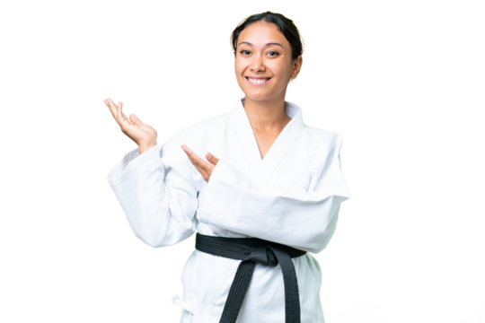 Young Uruguayan woman doing karate over isolated chroma key background extending hands to the side for inviting to come