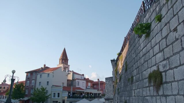 Ancient stonewalls and houses with church tower in old Zadar, Croatia, the Five Wells square