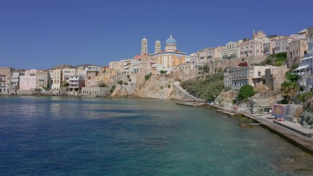 Aerial: Slow panoramic drone shot of Asteria beach in Ermoupoli of Syros island in Greece on a sunny day