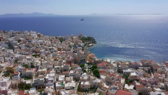Aerial: Slow panoramic drone shot of Asteria Beach in Ermoupoli of Syros island, Greece on a sunny day