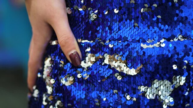 Hand detail blue dress sequins, shiny shimmering fabric, jewel glitter skirt, silver, light blue, dark blue, royal blue, nail polish, shining nails, elegant girl fashion, cinematic close-up shot.