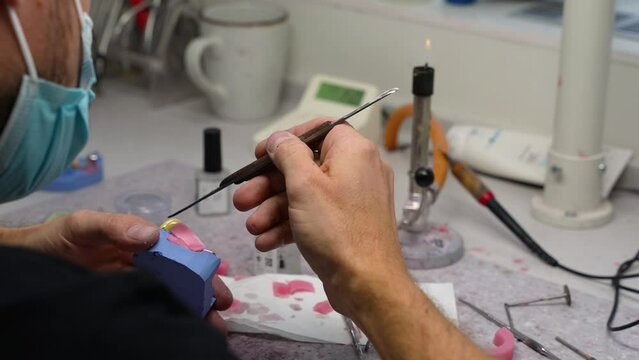Dental technician melting wax for artificial jow in dental prosthetic and making new teeth at the work-shop in small clinic