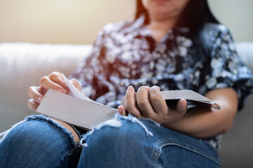 Stay home pastimes. Asian woman sitting in cozy sofa with open book indoors.