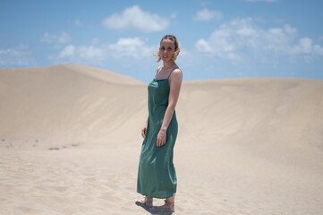 Blond young girl with green dress on the beach dunes