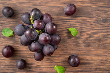 Delicious bunch of grapes fruit spilled over wooden table background.