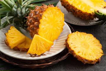 Fresh cut sliced pineapple in a plate over dark gray table background.