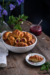 Traditional Ukrainian baked goods. Homemade crescents with edible rose jam and glass jar with jam on old wooden table.
