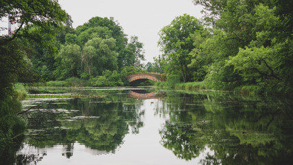 Lake of a park with a bridge making a beautiful water reflection on a cloudy day