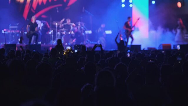 Crowd of people dancing during concert with glowing spotlights