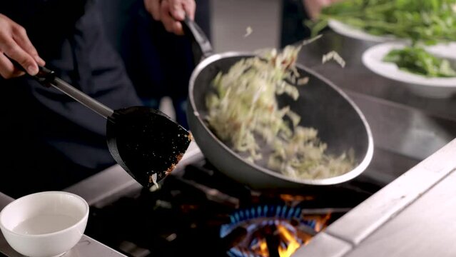Hands of professional chef working in restaurant holding hot frying pan cooking fried vegetables, cooker with uniform standing in front of stove preparing dinner for customer, lifestyles chef working