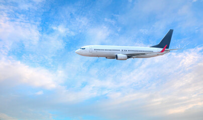 Fototapeta premium White passenger airplane flying in the sky amazing clouds in the background - Travel by air transport