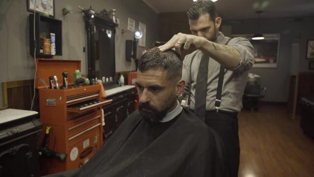 Hairdresser Using Electric Razor And Comb In Barber Shop - close up